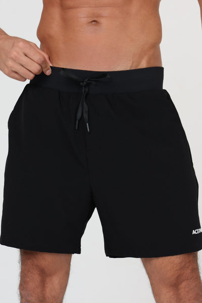 Homme portant le short padel ACE ONE noir sur le court