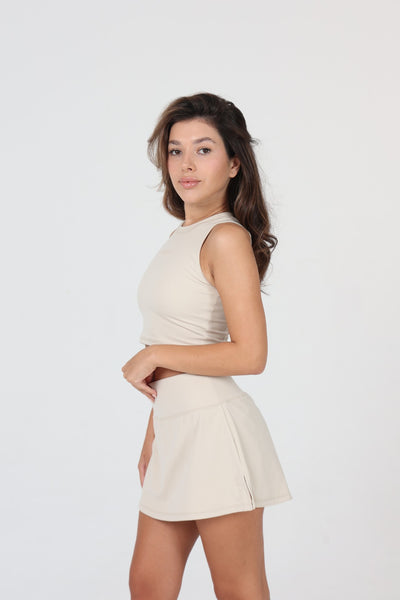 Femme au service en skort padel ACE ONE beige
